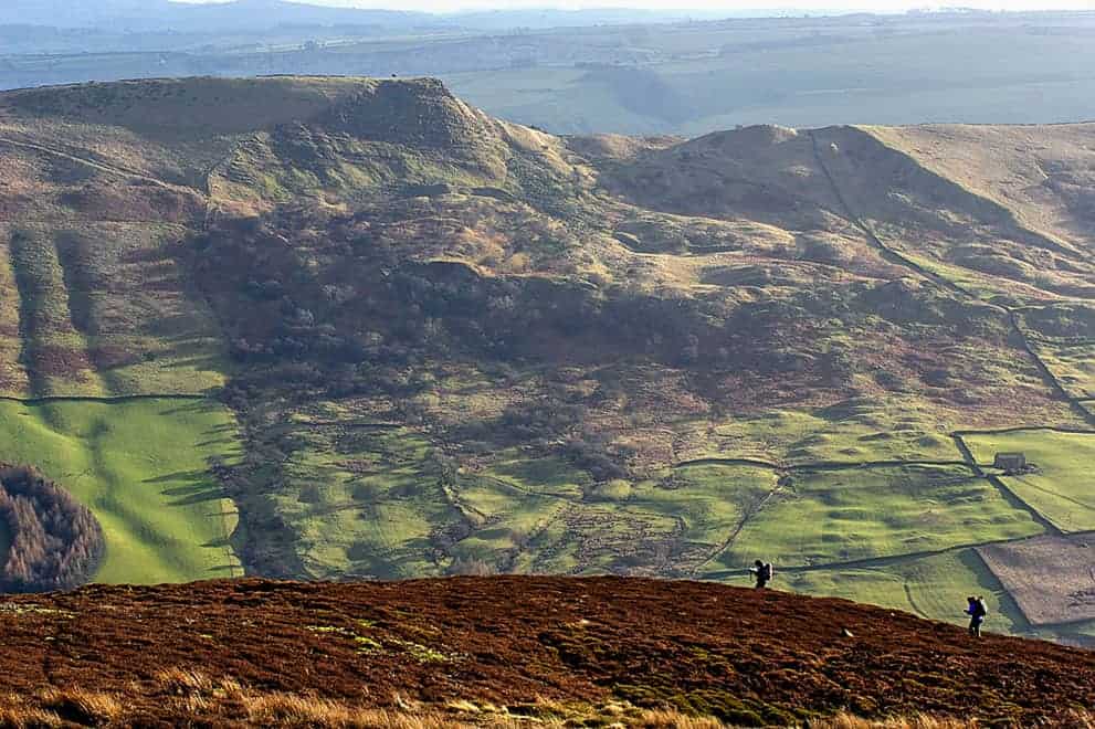 Two people navigating on Edale moor with Mam Tor in the background on a Peak District navigation course.
