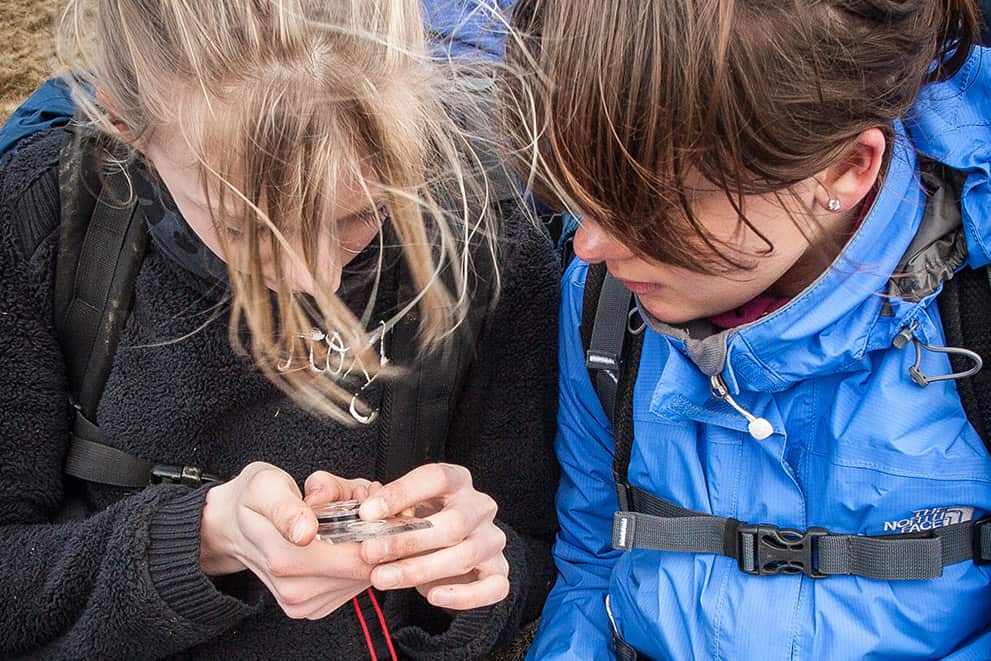 Two girls learning to use a compass and map read on an Introduction to Navigation course in the Peak District