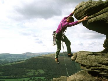 A rock climber on a Mountain Training instructor course nearing the top of a climb in the Peak District