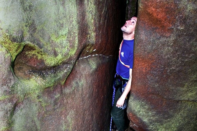 A man looking up as if he was stuck rock climbing on Stanage Edge