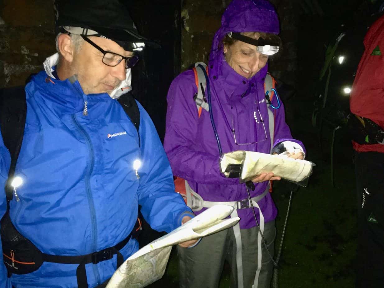 A man and a lady using a map and compass whilst learning to navigate at night on a navigation course in the Peak District.
