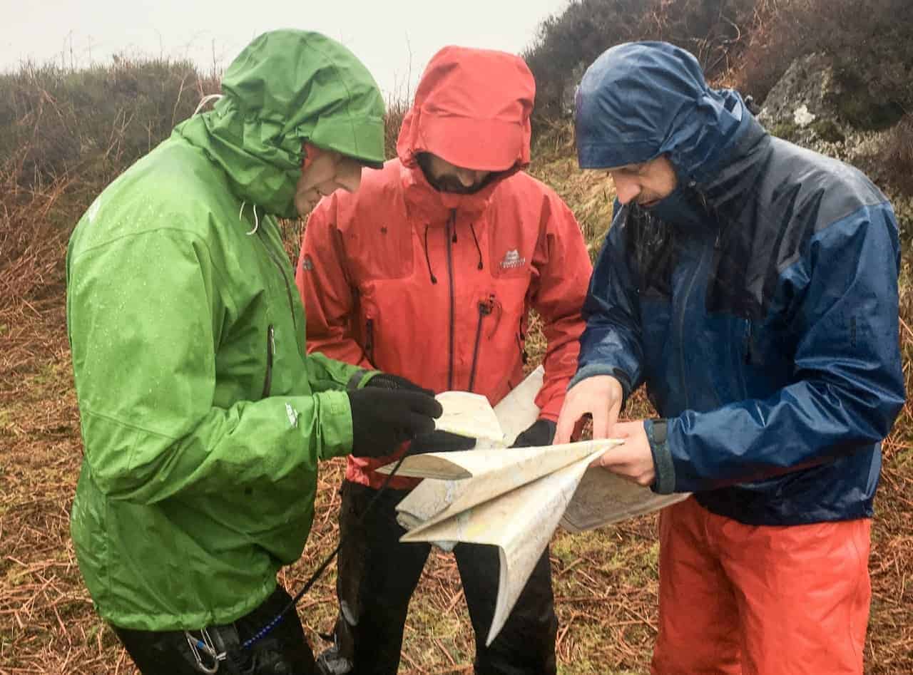 3 men study their maps whilst teaching navigation on the hills in the Peak District