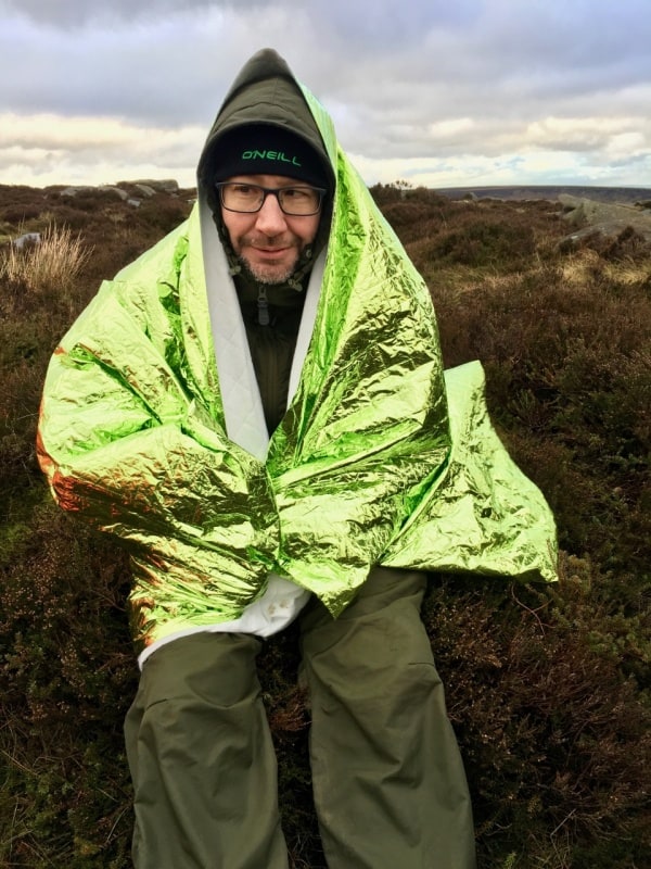 A man practices with an emergency blanket on a Mountain Leader training course.