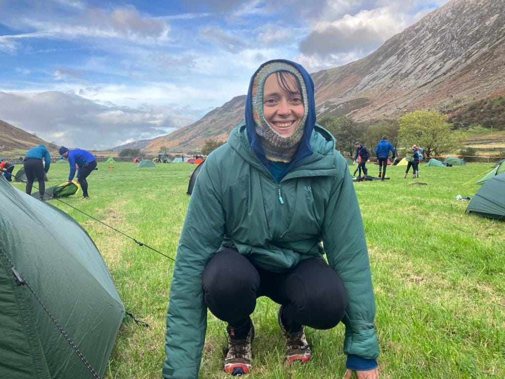 A woman wearing a Rab synthetic jacket and multicoloured balaclava at overnight camp at the OMM
