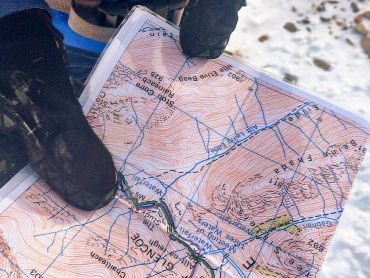 A gloved hand holding a map whilst practicing navigation