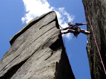 A man rock climbing on Stanage Edge on a mountaineering skills course
