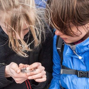 Two girls learning to use a compass and map read on an Introduction to Navigation course