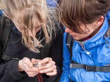 Two young girls study a compass whilst on Peak District navigation courses