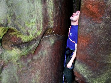 A man looking up as if he was stuck rock climbing on Stanage Edge