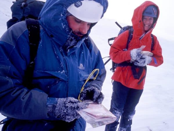 Intermediate navigation by two people with map and compass in snow