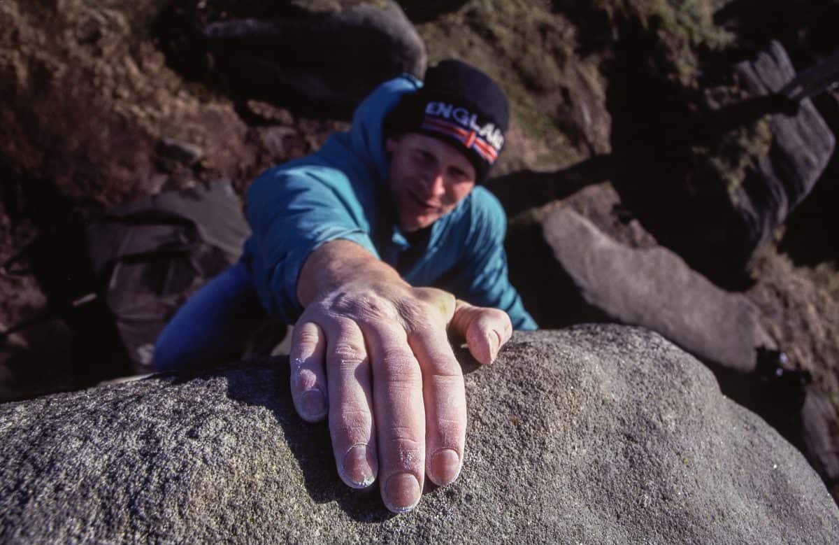 A man bouldering on gritstone in the Peak District.