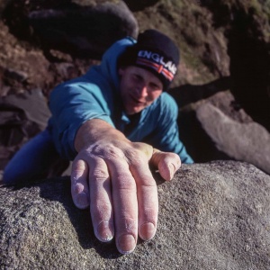 A man bouldering on gritstone in the Peak District.