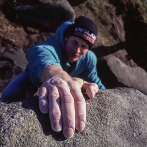 A man bouldering on gritstone in the Peak District.