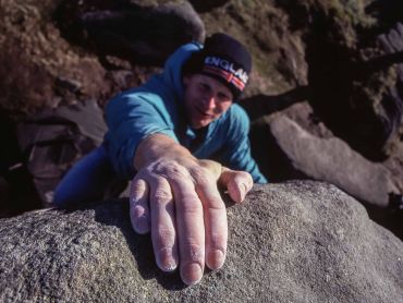 A man bouldering on gritstone in the Peak District.