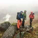 A group of three men in pouring rain on a Mountain leader assessment in Wales.
