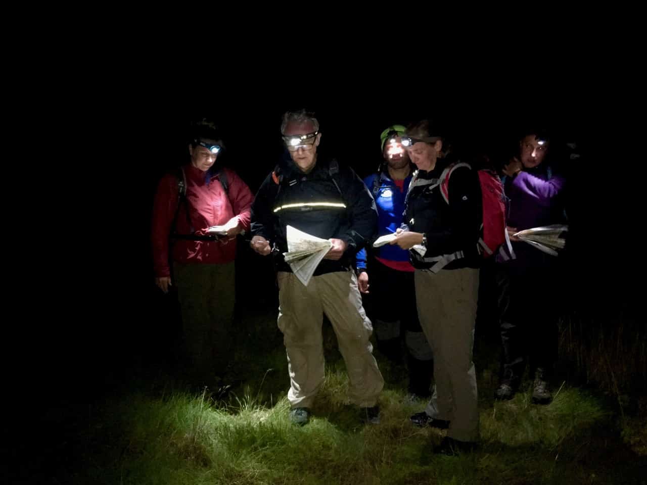 A group practicing night navigation with map and compass
