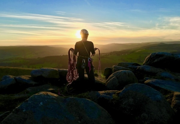 Rock climbing in the peak district. A rock climber coils a rope looking over Stanage edge.