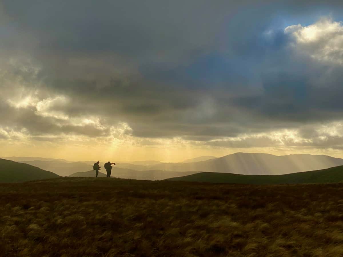 Three people standing on a mountain near Helvellyn on a guided walking holiday in the Lake District.
