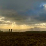 Three people standing on a mountain near Helvellyn on a guided walking holiday in the Lake District.