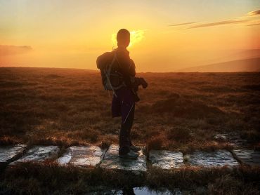 A lady walking in the sunset on the Edale Skyline challenge.