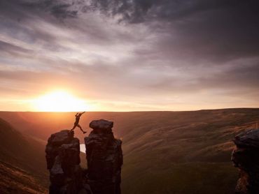 A man strides between two rocks at sunset on a fell running course in the Peak District