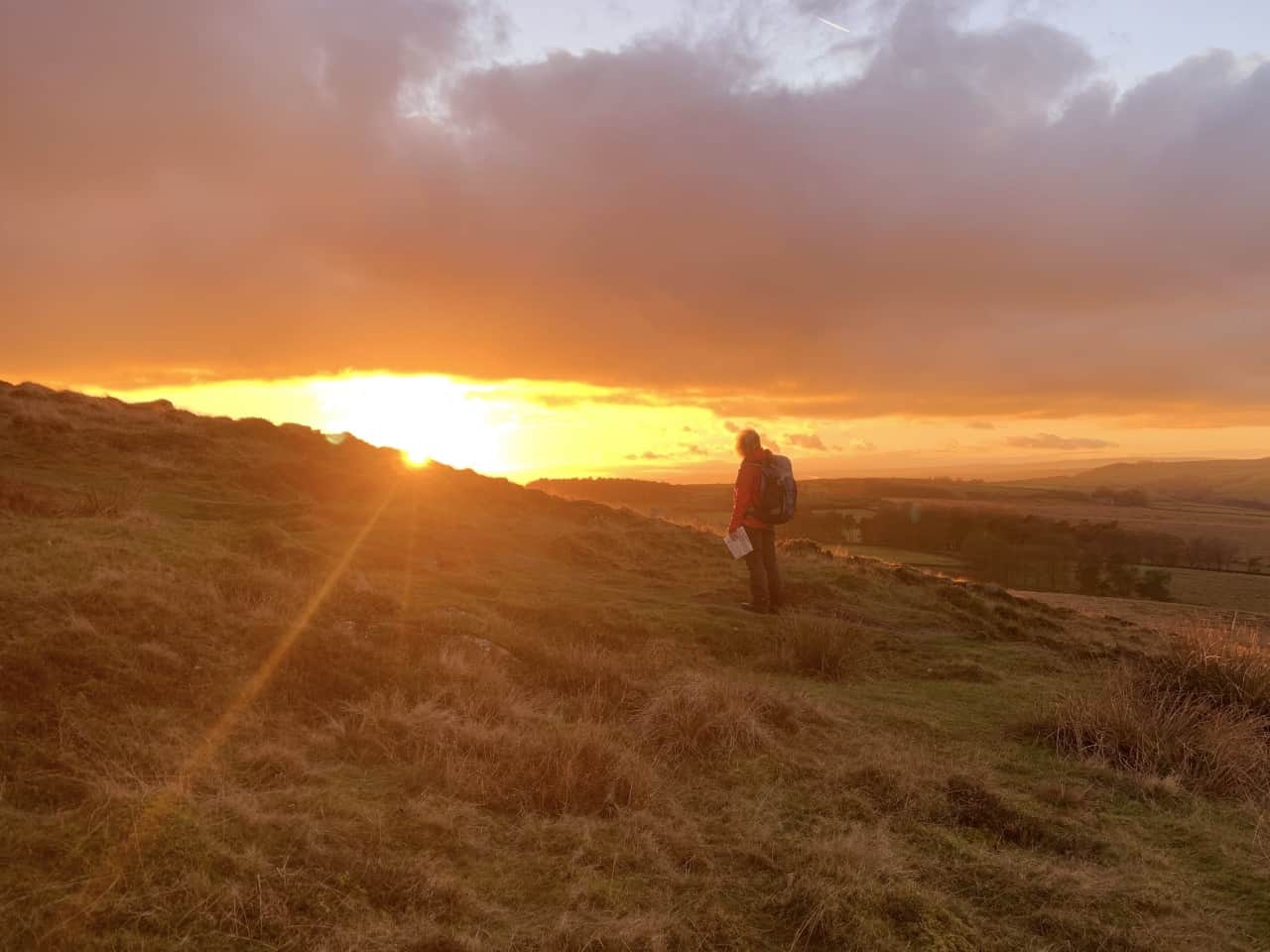A lady stares into the sunset on a Lowland Leader Award training course in the Peak District