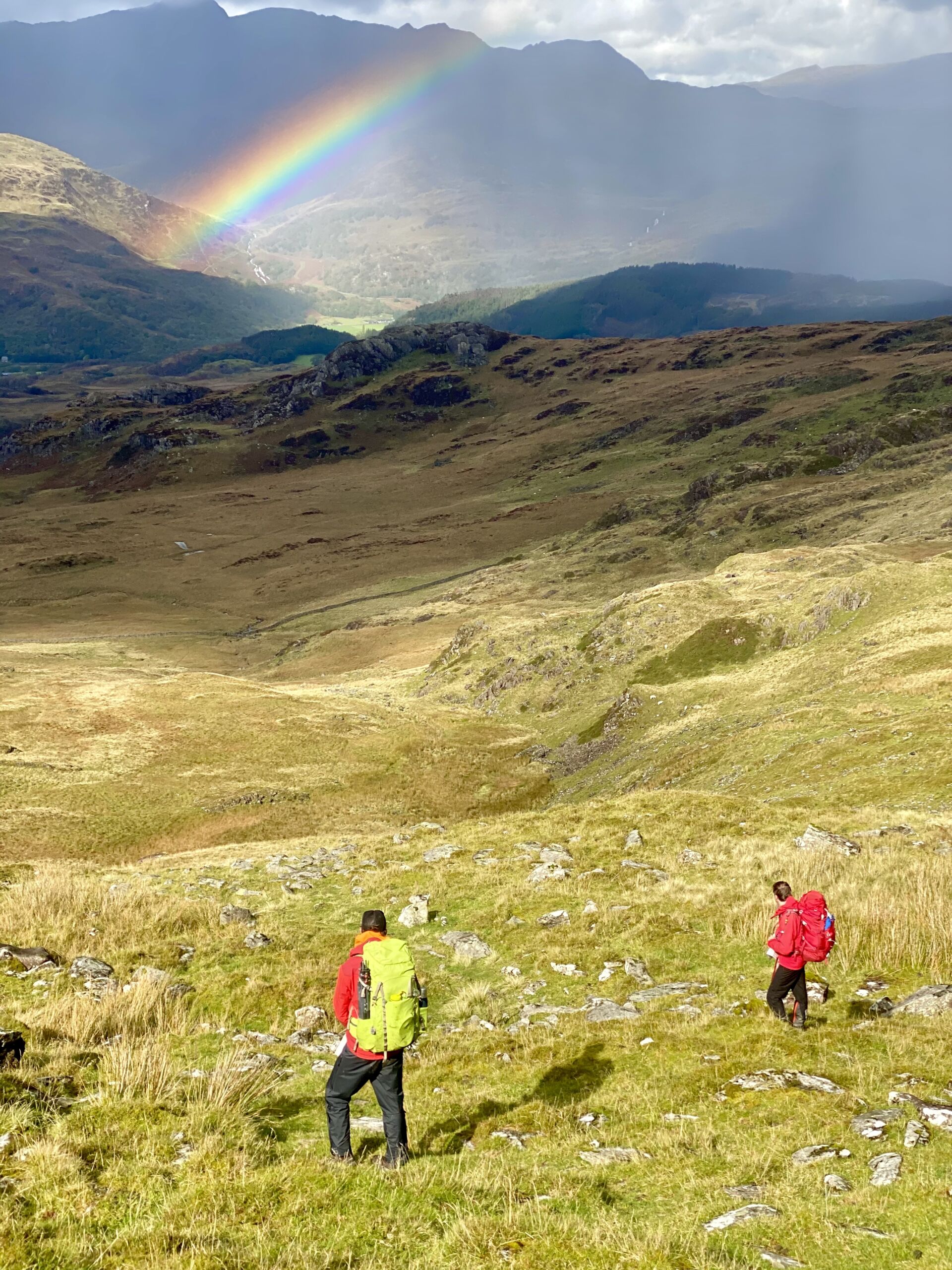 Two mountaineers admire a rainbow overlooking Yr Wyddfa (Snowdon)