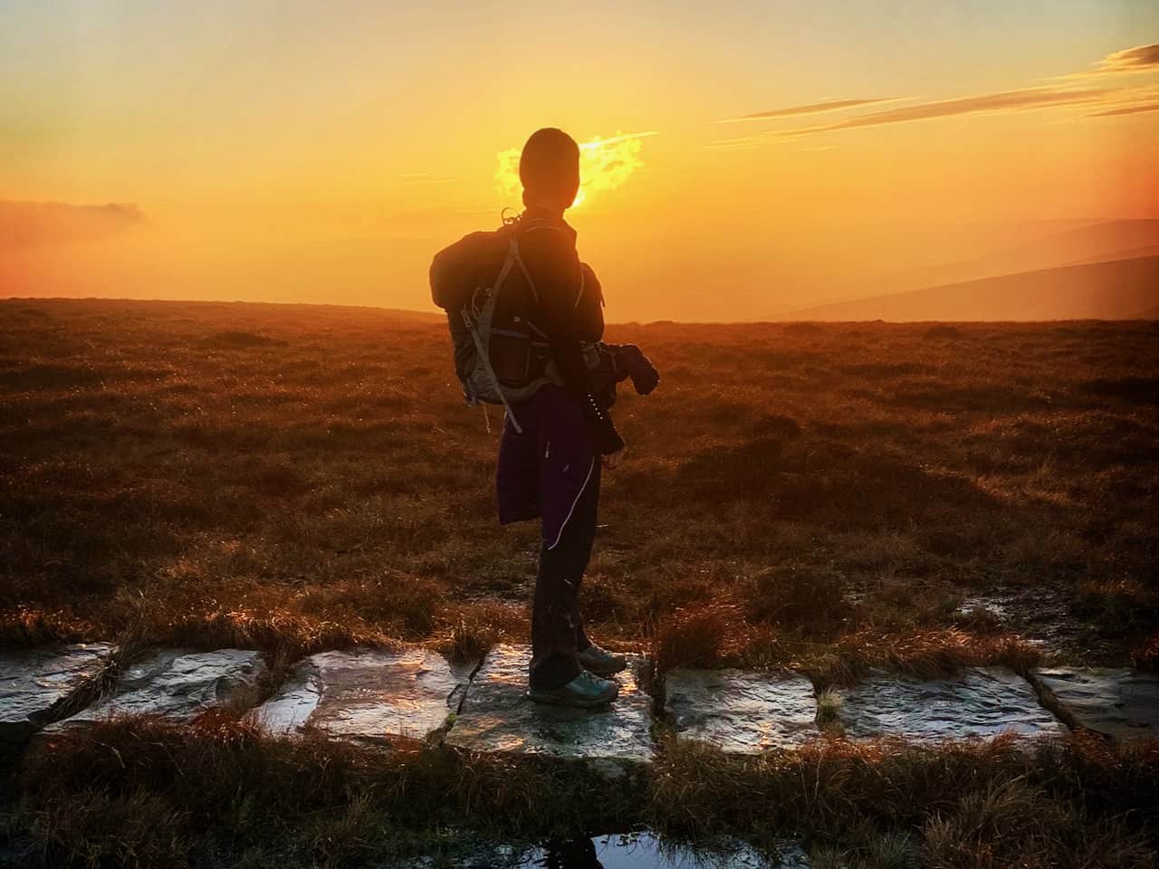 A lady stares into the sunset on a Lowland Leader Award training course in the Peak District