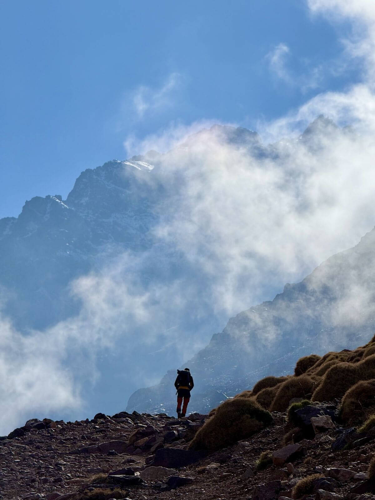 A man walking in the Atlas mountains in Morocco on the approach to Toubkal in winter.