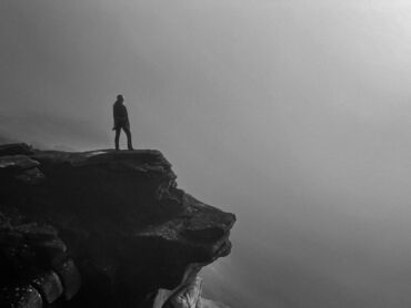 A lady overcoming her fear of heights, looking over Stanage Edge in the mist