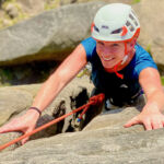A lady learning how to rock climb on a introduction to rock climbing course in the Peak District.
