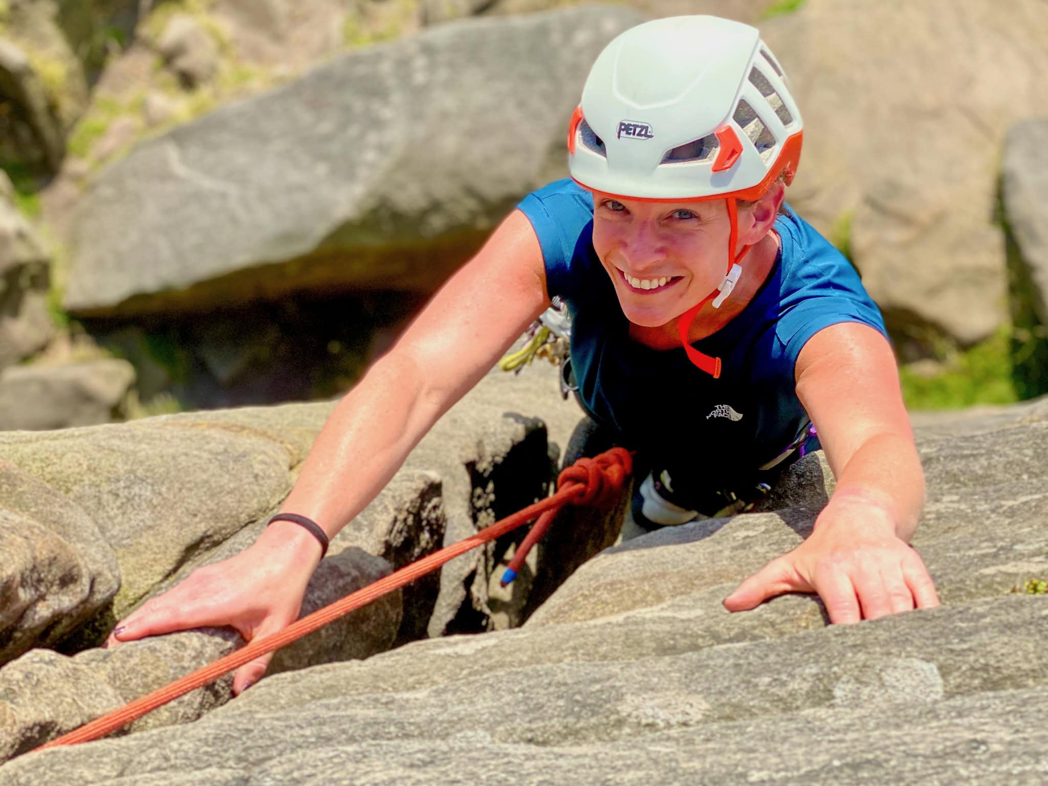 A lady learning how to rock climb on a introduction to rock climbing course in the Peak District.
