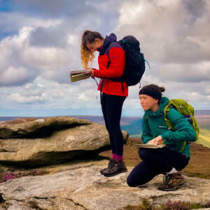 Two women in the Peak District looking at their map and compass whilst on an introduction to navigation course.