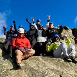 A group of ladies on a rock climbing taster day, sat on rocks in the Burpage valley in the Peak District.