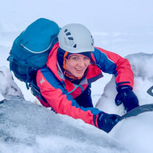 A lady winter mountaineering in Scotland with an ice axe.