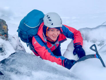A lady winter mountaineering in Scotland with an ice axe.