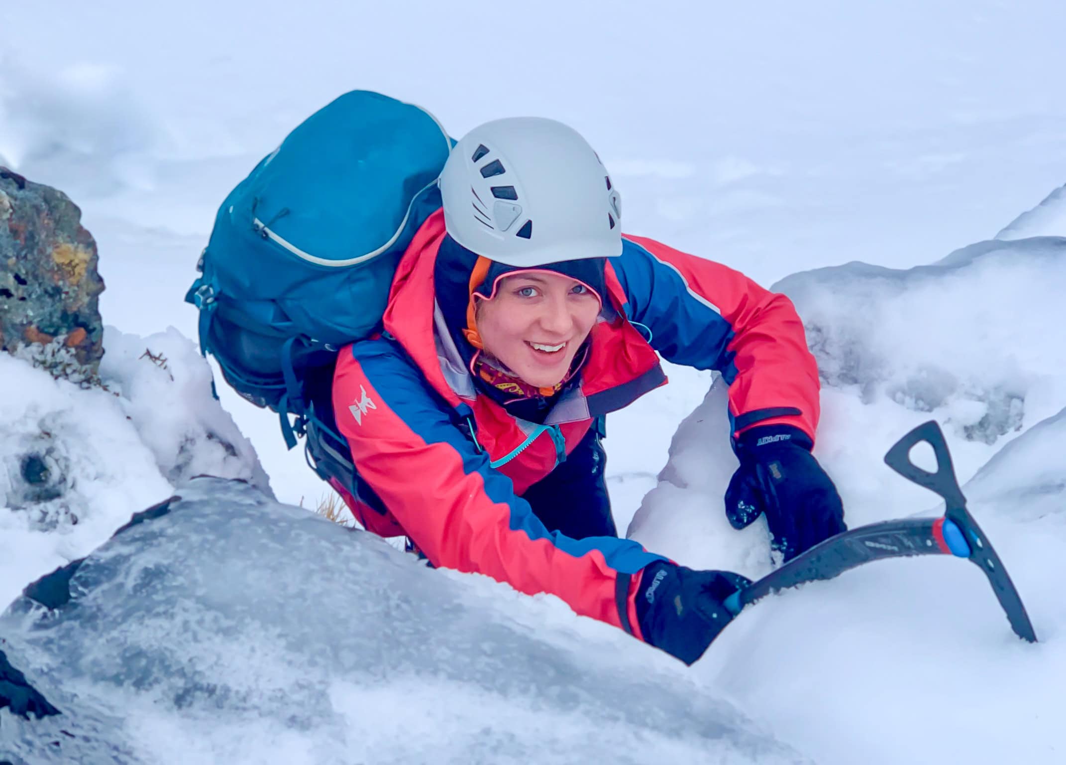 A lady winter mountaineering in Scotland with an ice axe.