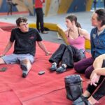 A group on a Climbing Wall instructor course sitting on mats in a climbing wall.