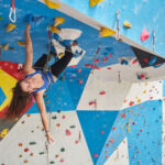 Young woman climbing on a climbing wall for a climbing wall instructor assessment.