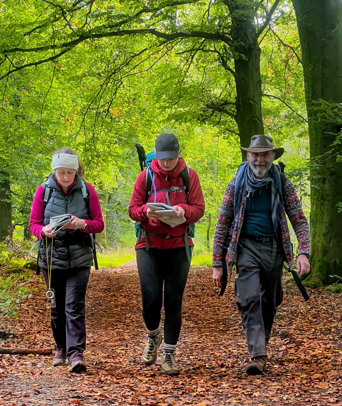 Three people walk down a path on Chatsworth estate on a Lowland Leader course in the Peak District.