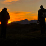 Two men look at their maps at sunset on a Mountain Leader assessment in the Moelwyns.