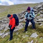 A woman confidence roping a man on a Mountain leader training course in Wales.