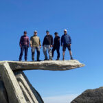 A group stands on the Cantilever stone on Glyder Fach on a Mountain Leader course.
