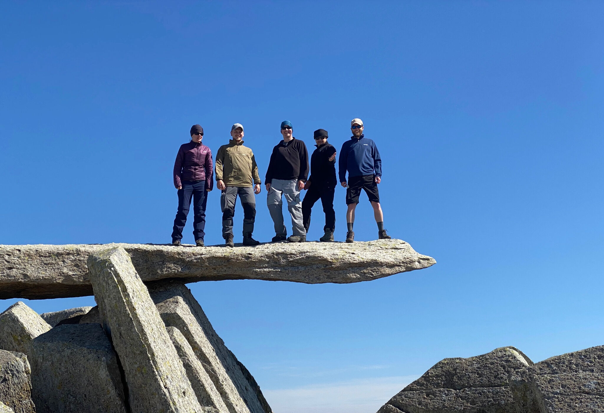 A group stands on the Cantilever stone on Glyder Fach on a Mountain Leader course.