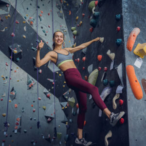 A woman bouldering on a bouldering wall.
