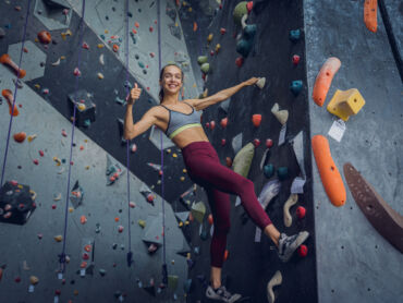 A woman bouldering for a bouldering wall instructor assessment course.