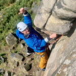 A man climbs a classic rock climb on Stanage