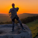 A man coiling a rope at sunset after lead climbing in the Peak District.