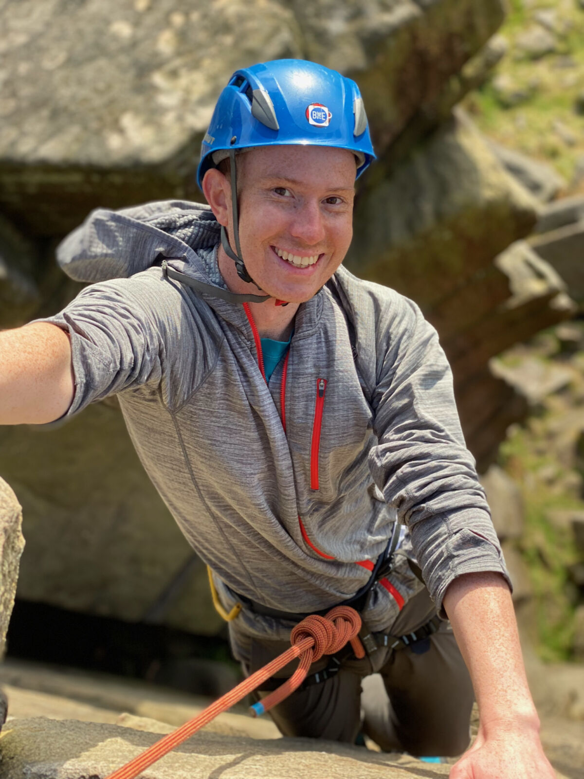 A man climbing a rock face with a rope on a rock climbing course on Stanage Edge in the Peak District.
