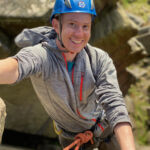 A man climbing a rock face with a rope on a rock climbing course on Stanage Edge in the Peak District.